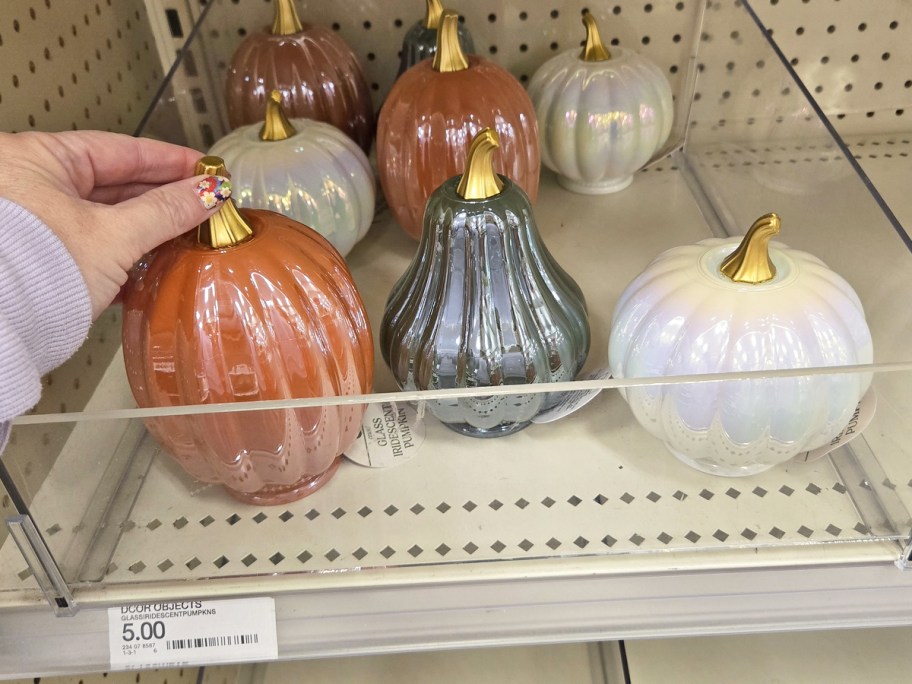 hand grabbing a glass pumpkin from store shelf