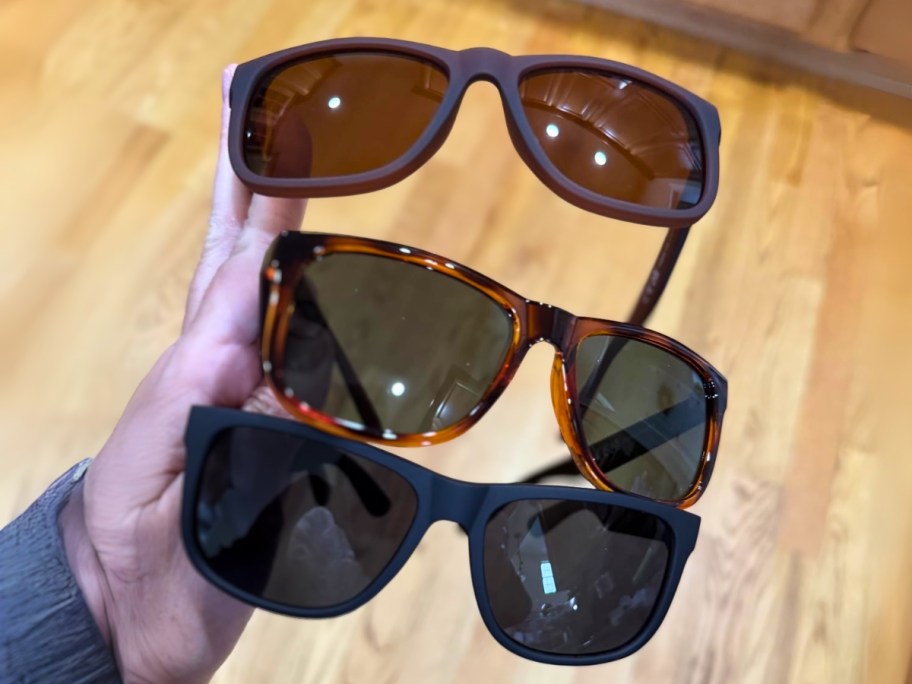 hand holding 3 pairs of sunglasses