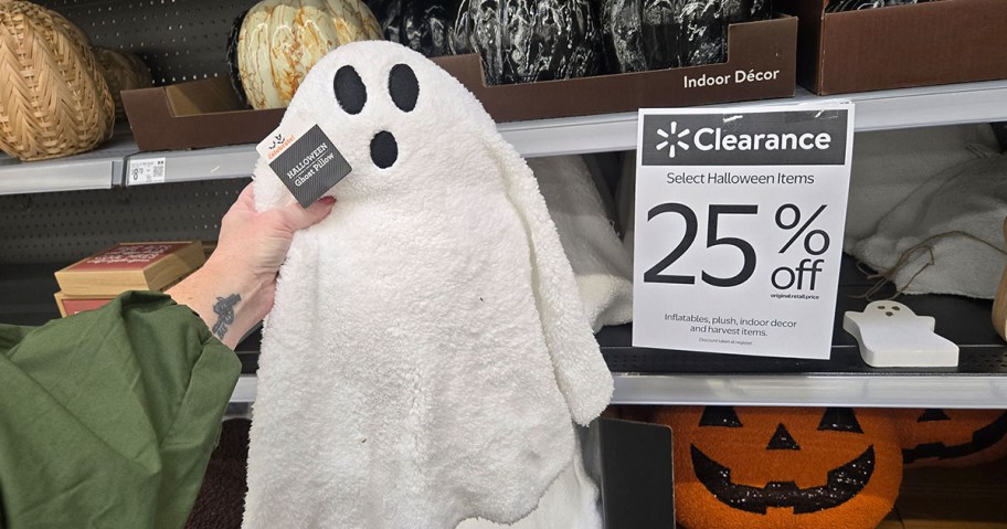 Halloween Ghost Pillow being held in Walmart next to a clearance sign