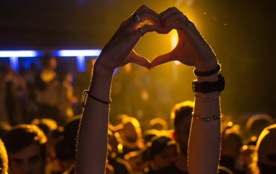 Person holding up hands in shape of a heart at concert