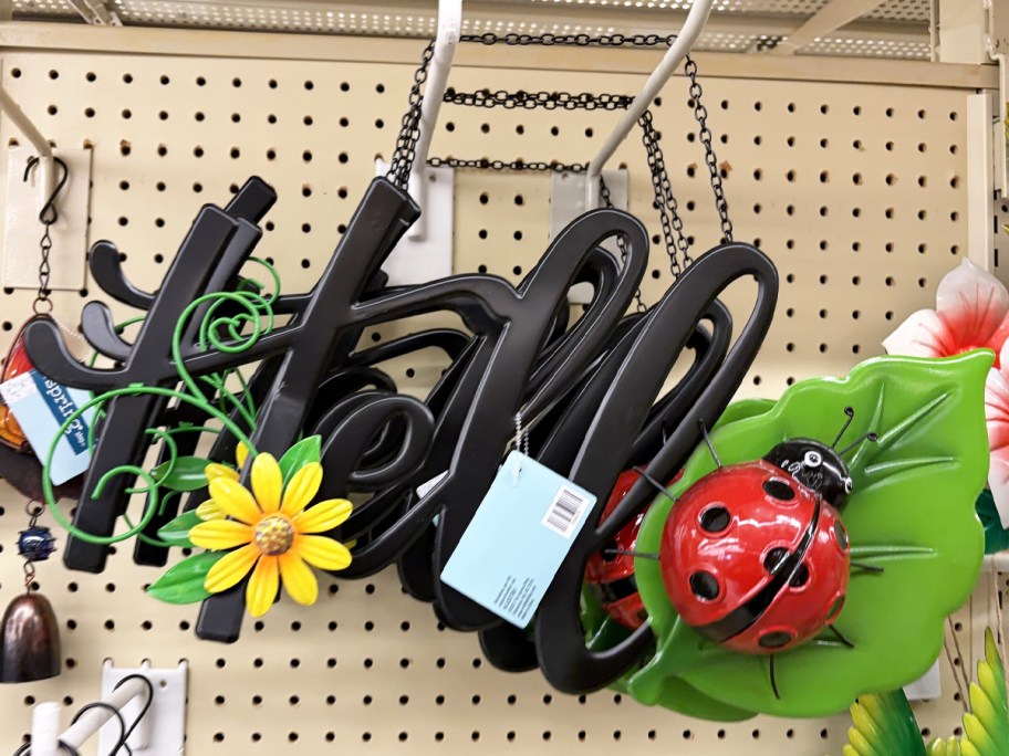 metal sign that says hello with a flower and a ladybug