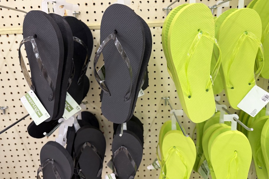 black and green pairs of flip flops hanging from store display wall