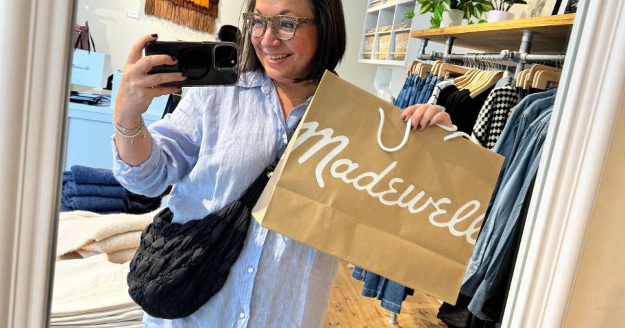 Woman taking a picture in a mirror holding a Madewell bag