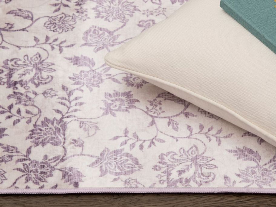 Mainstays 3'x5' Lavender Floral Faux Fur Indoor Accent Rug with pillows on top of it