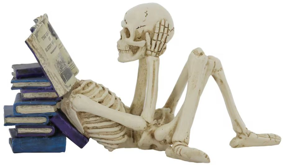a Skeleton figurine reading a book next to a stack of books