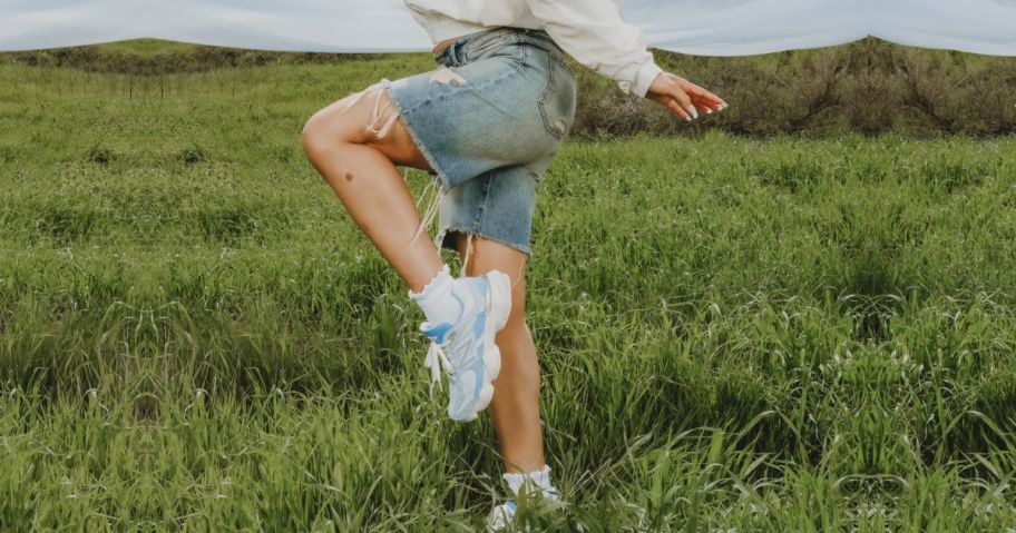 woman wearing baby blue new balance 9060s in a field of grass