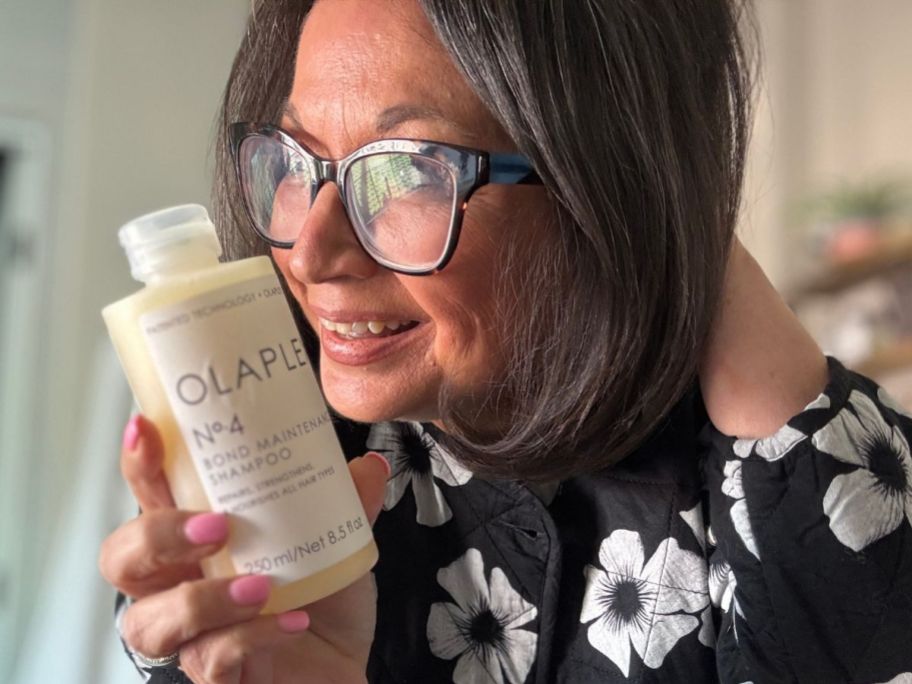 Woman holding a bottle of Olaplex next to her hair