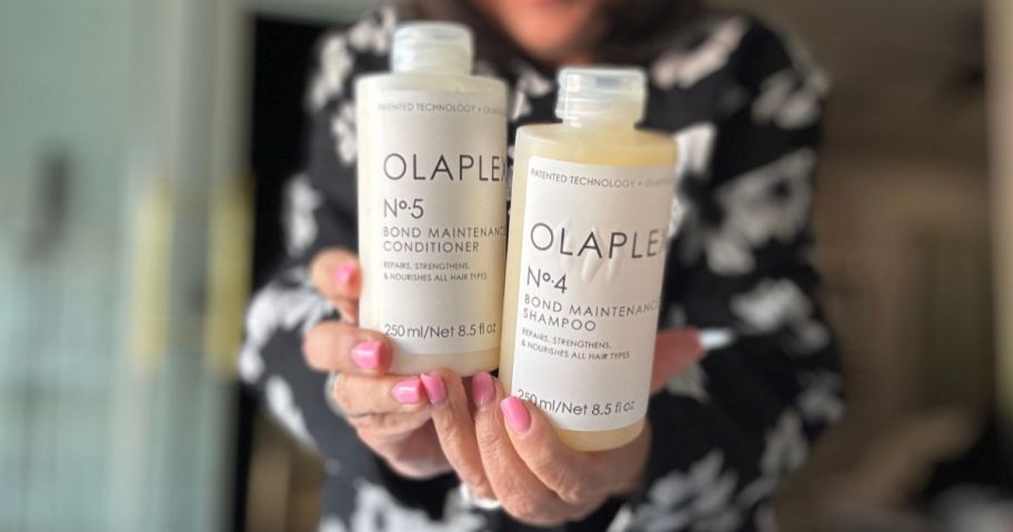 Hands holding two bottles of Olaplex Shampoo & Conditioner
