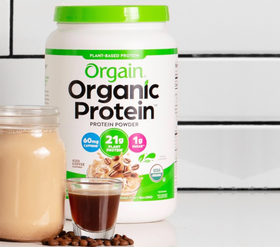 container of orgain protein powder, espresso shot, and drink glass on kitchen counter