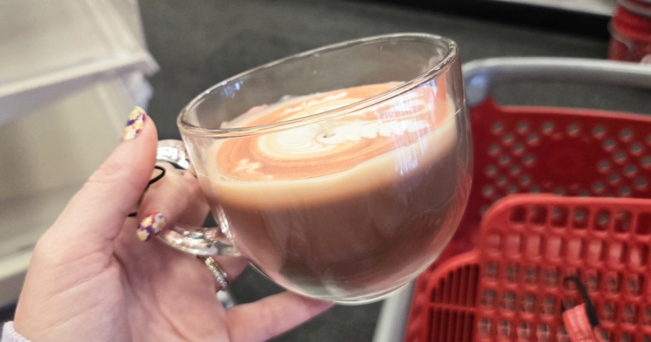 hand holding up a pumpkin latte candle in a glass mug