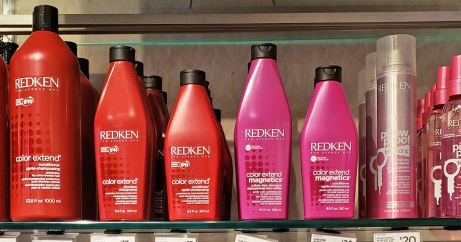red and pink bottles of Redken Shampoo & Conditioner on store shelf