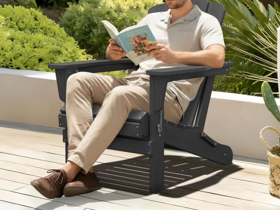 man sitting in Rosecliff Heights Wolak High Density Polyethylene Folding Adirondack Chair on patio