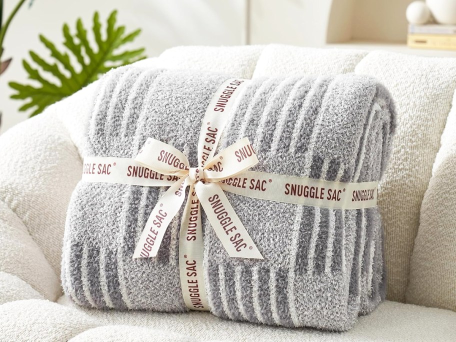 folded grey throw blanket wrapped in ribbon on a couch