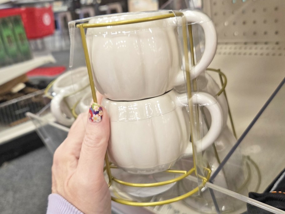 hand holding a set of white stackable pumpkin mugs