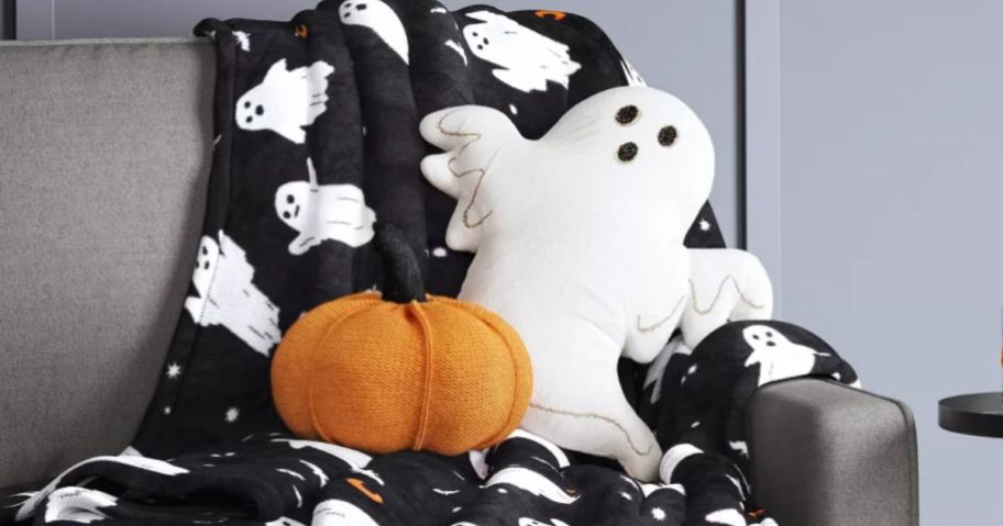 Hydde & Eek! Boutique Pumpkin and Ghost Figural Halloween Throw Pillows on a bl;anket on a couch