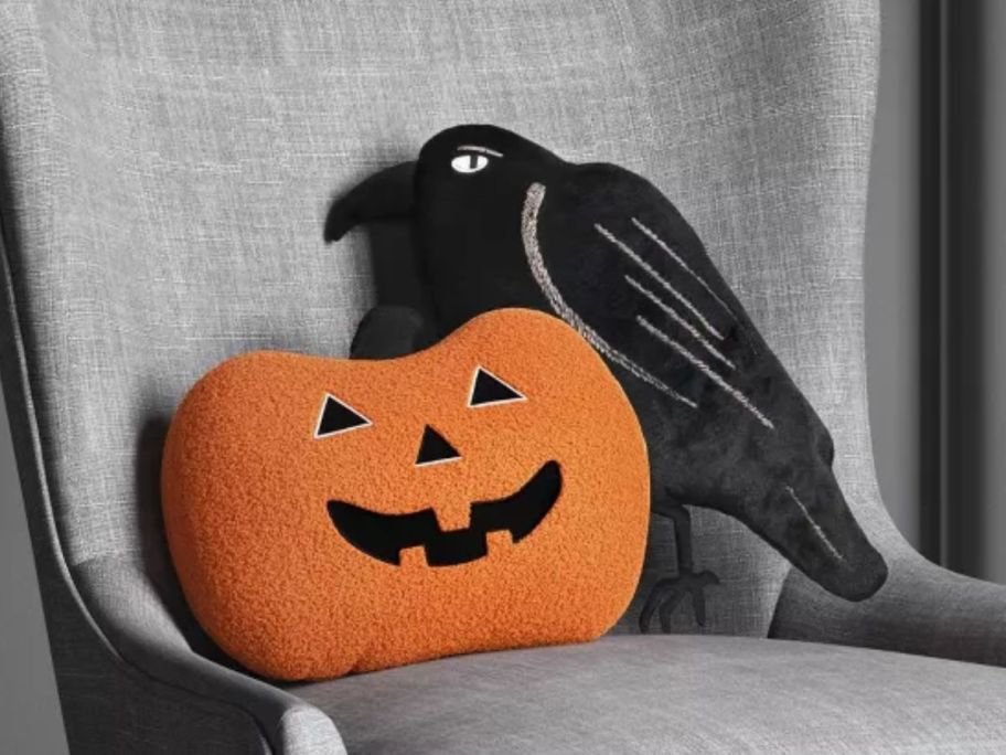 Hyde & Eek! Boutique Jack O'Lantern and Raven Throw Pillows on a chair