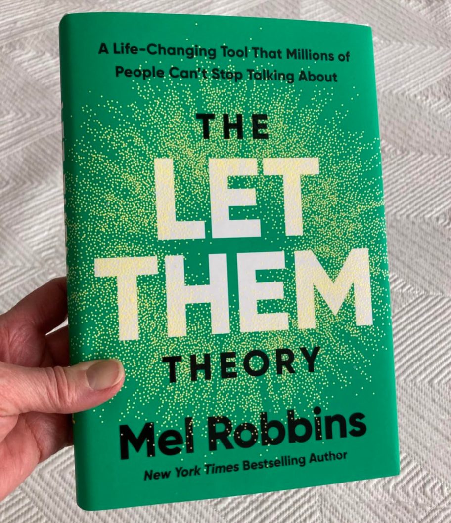 hand holding the let them theory book