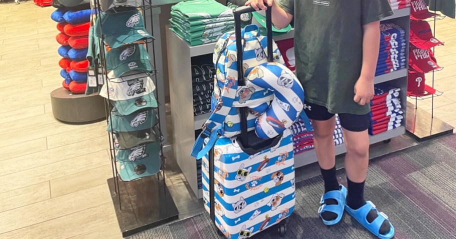 kids standing in airport with a matching luggage, backpack, and neck pillow set