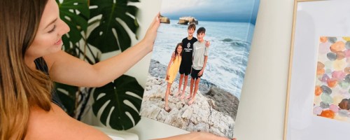 woman holding canvas print with kids on beach on wall