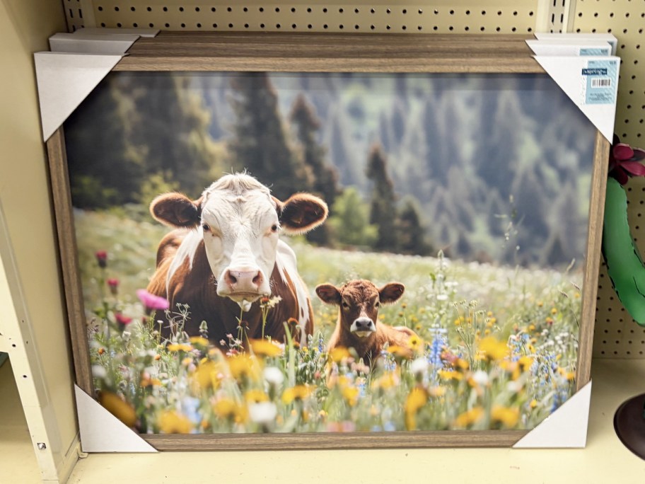 framed print of cows laying in flowers
