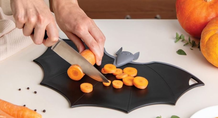 person chopping carrots on a bat cutting board