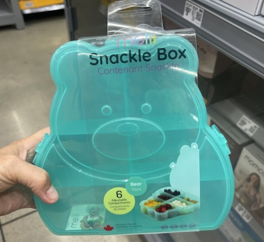 a womans hand holding a blue bear snackle box