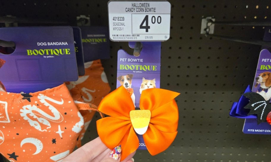 a woman's hand holding a candy corn pet bow tie