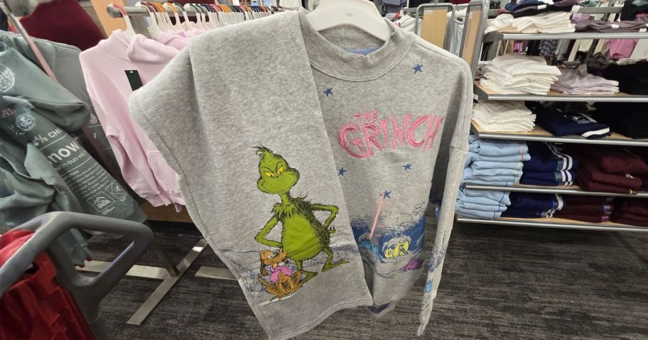 grinch sweater shirt with pants draped over them in store