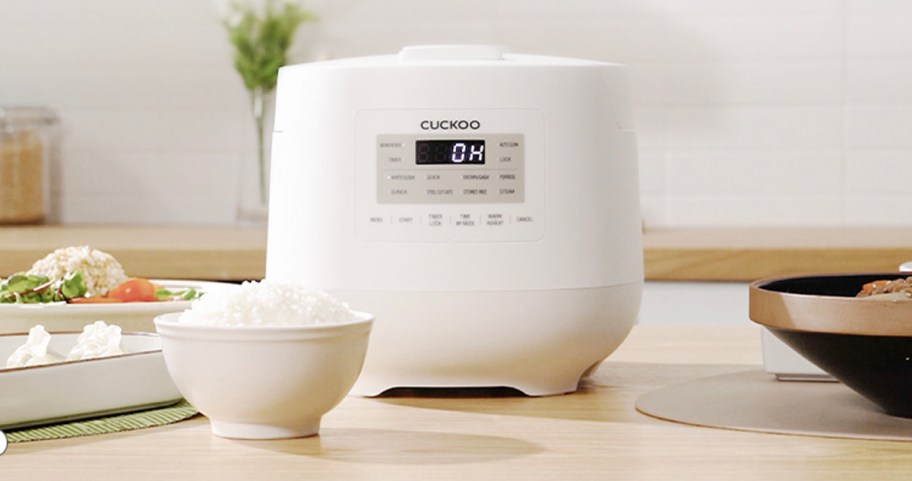 white ricer cooker with bowl of rice on table