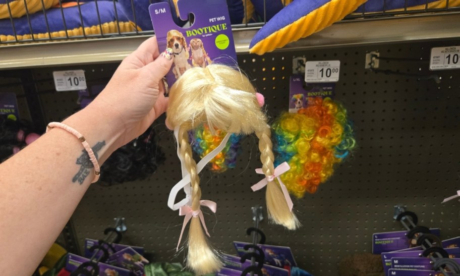 a womans hand holding a blonde braided dog wig