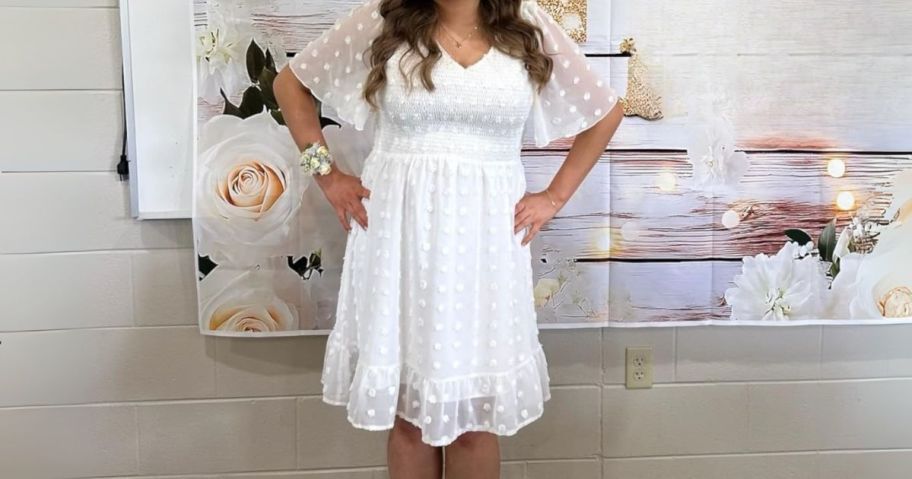 woman wearing short white dress in front of backdrop