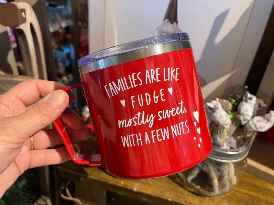a woman s hand holding a family fudge insulated coffee