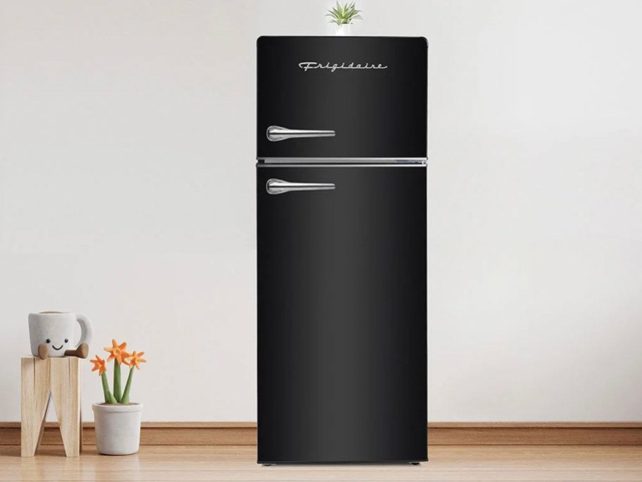 black two door retro fridge with plant on top