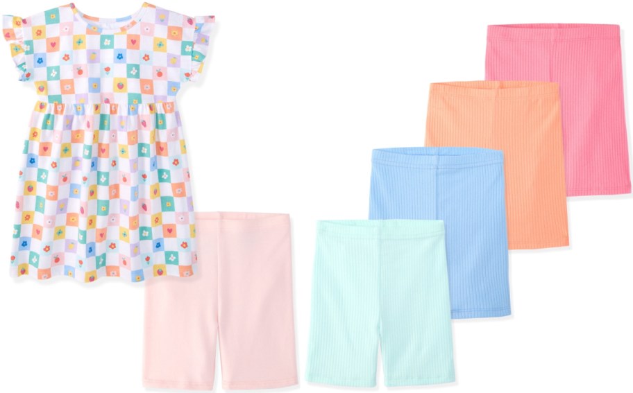 A colorful dress with a pattern of squares and shapes, next to five pairs of shorts in various colors: pink, blue, orange, peach, and light green.