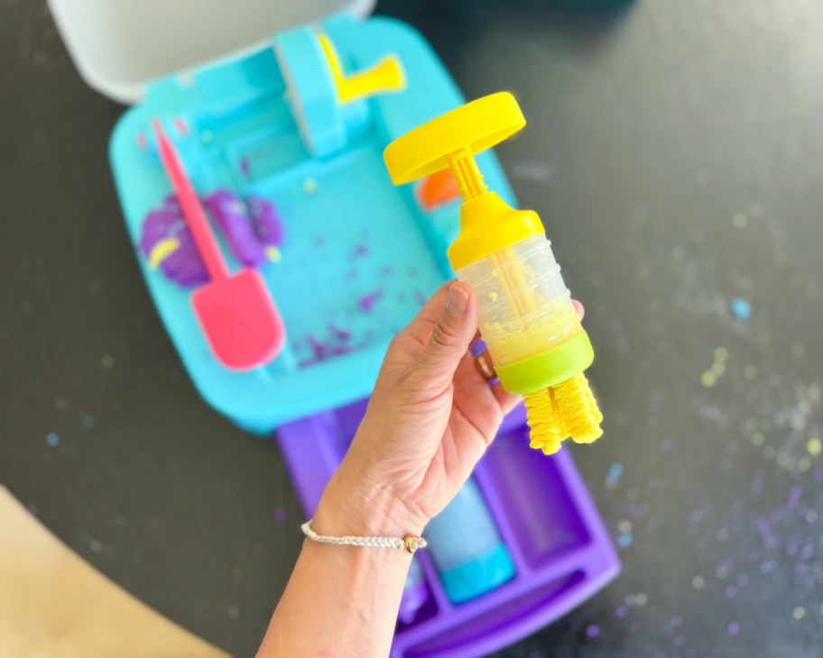 hand holding play dough spinner with yellow dough