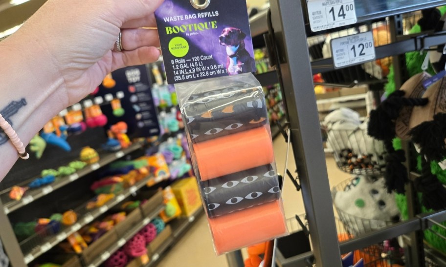 a womans hand holding a 8 pack of waste bags