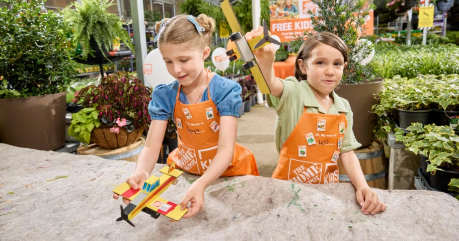boy and girl in orange aprons playing with toy planes