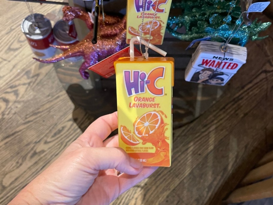 a womans hand holding a high c juice box ornament