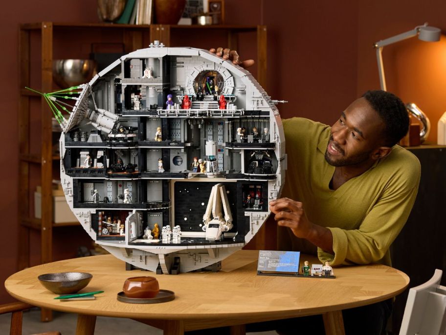 man holding LEGO Star Wars Death Star on table