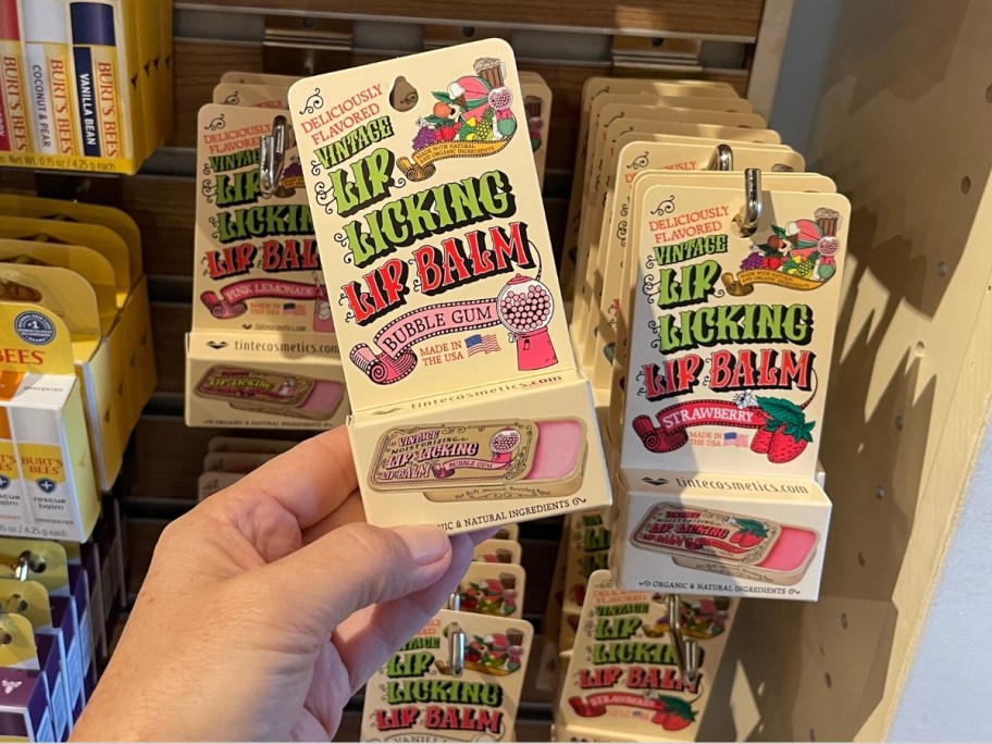 womans hand holding a lip balm tin