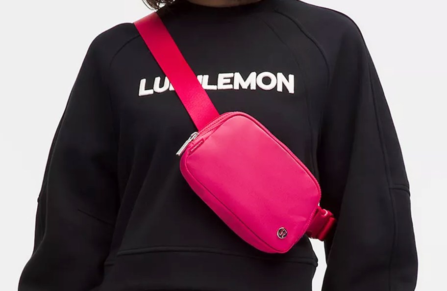 woman in a black lululemon sweatshirt with a pink belt bag across her chest