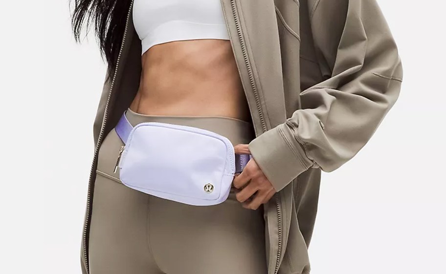 woman in brown leggings with a light purple belt bag