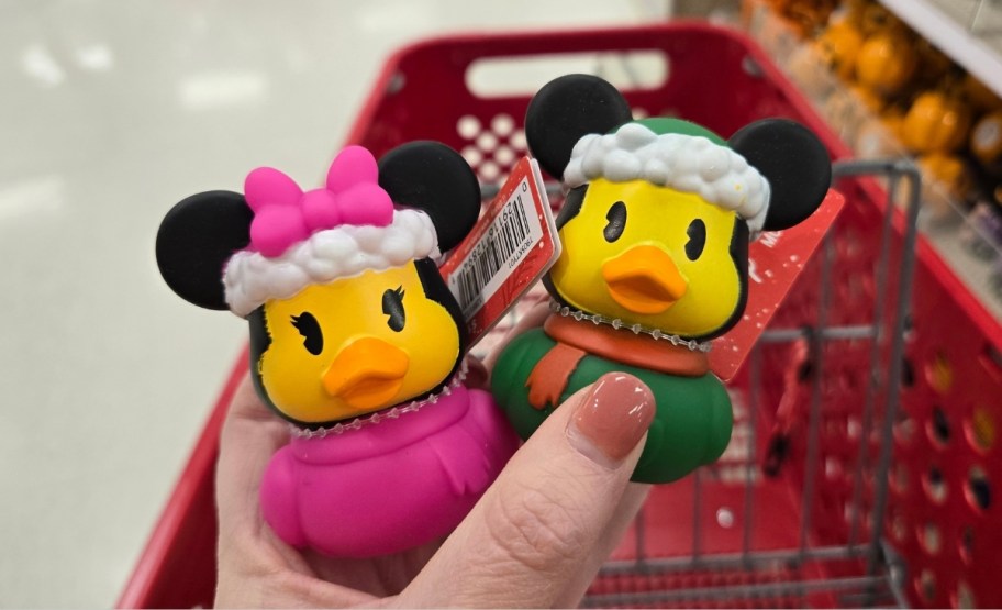 a womans hand holding minnie and mickey mouse holiday themed rubber ducks