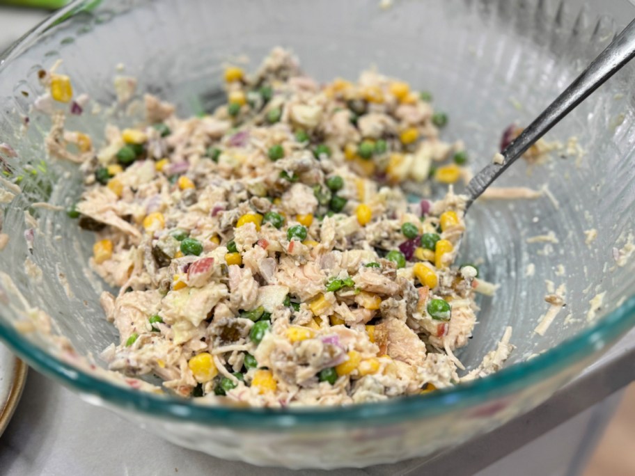 mixing up wasabi chicken salad in a glass bowl 