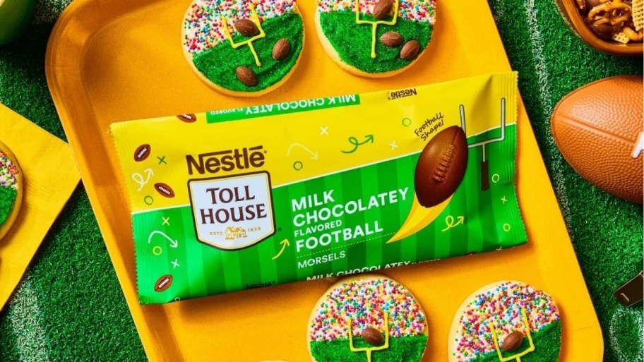 a bag of nestle football chocolate morsels on a yellow tray with decorated cookies