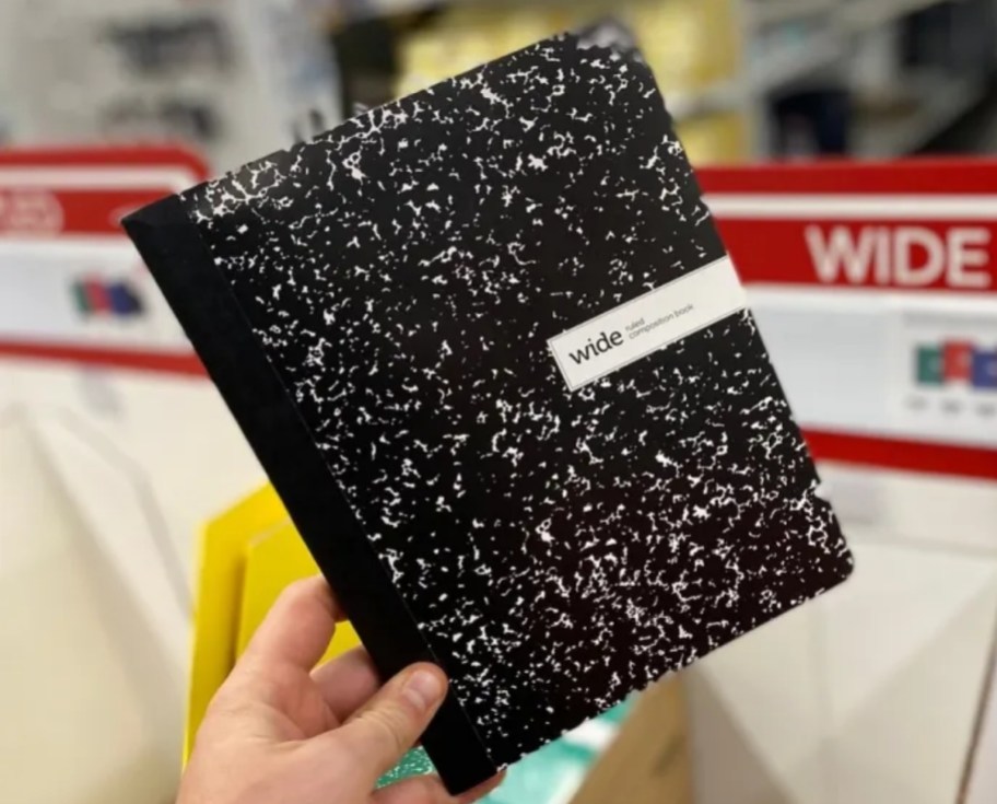 a mans hand holding composition book at Office Depot