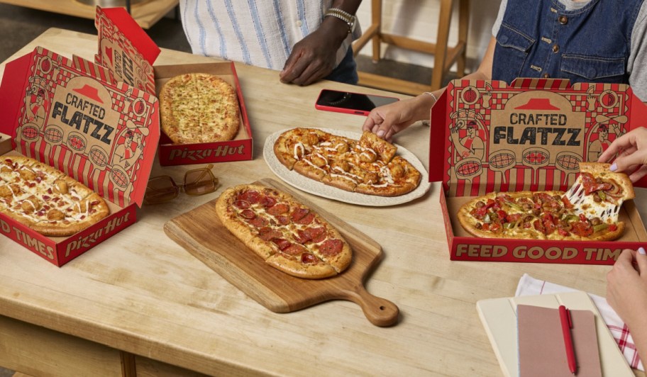 many people enjoying flatbread pizza in boxes