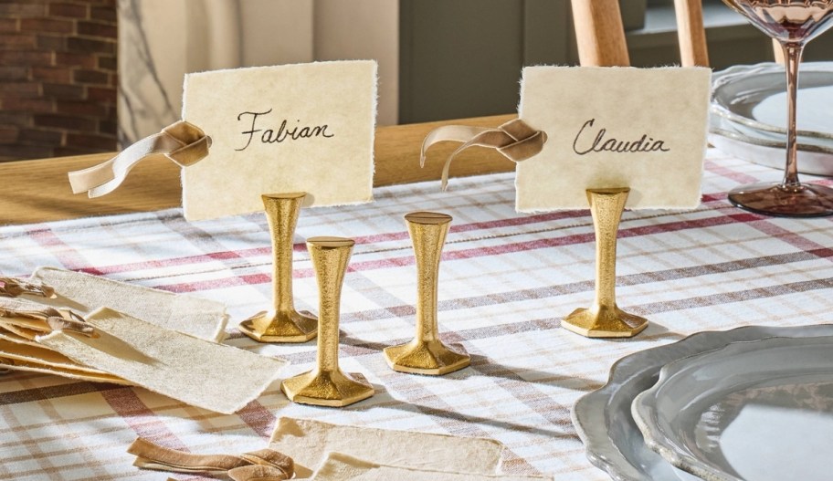 4 brass place card holders on a dining table