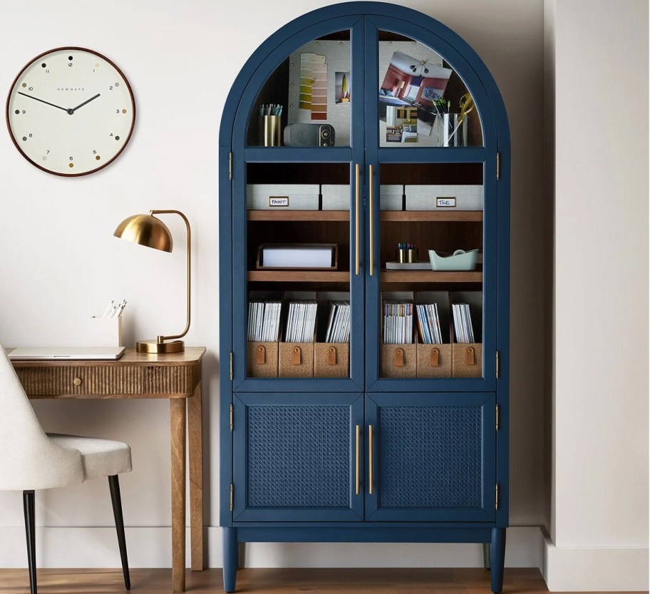blue arch cabinet with books and office supplies inside