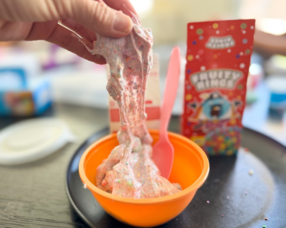 hand grabbing cereal slime out of orange bowl